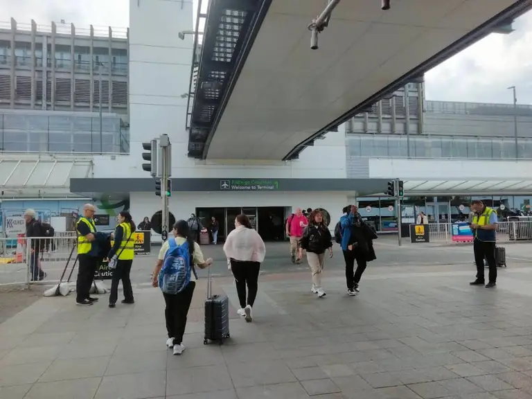 Travellers with luggage outside an airport terminal