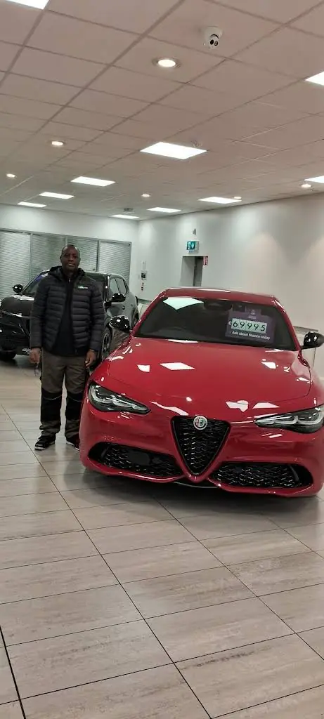 Man beside a red car in a showroom