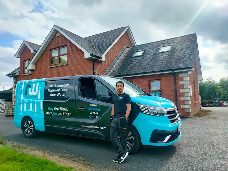 Worker beside a branded service van outside a building